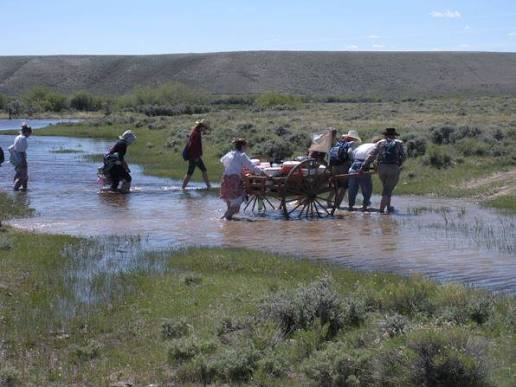 Trekkers pulling a handcart across a river
